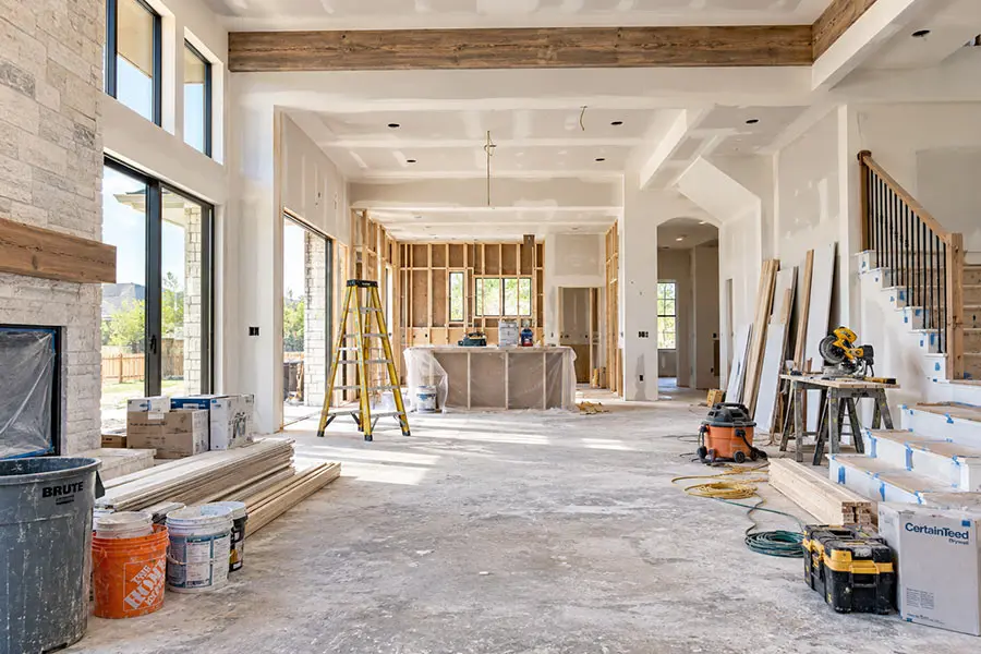 Interior home remodeling project in progress with unfinished drywall, exposed framing, construction tools, and building materials. Interior home remodeling project in progress with unfinished drywall, exposed framing, construction tools, and building materials.